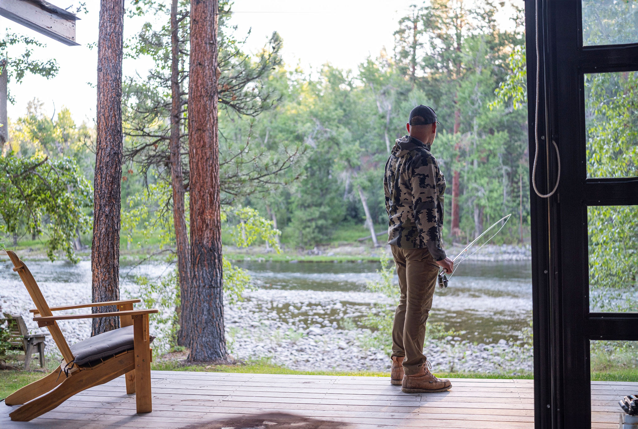 Angler stepping off the deck toward the river at dawn