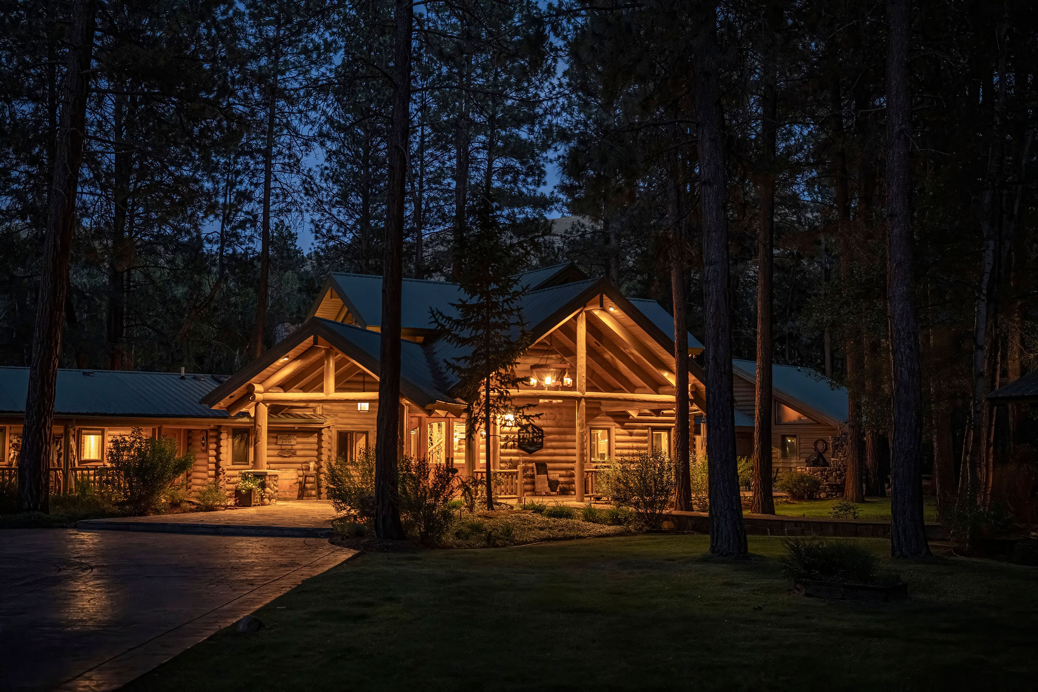 The Bitterroot Mile Club lodge glowing at twilight among the pines